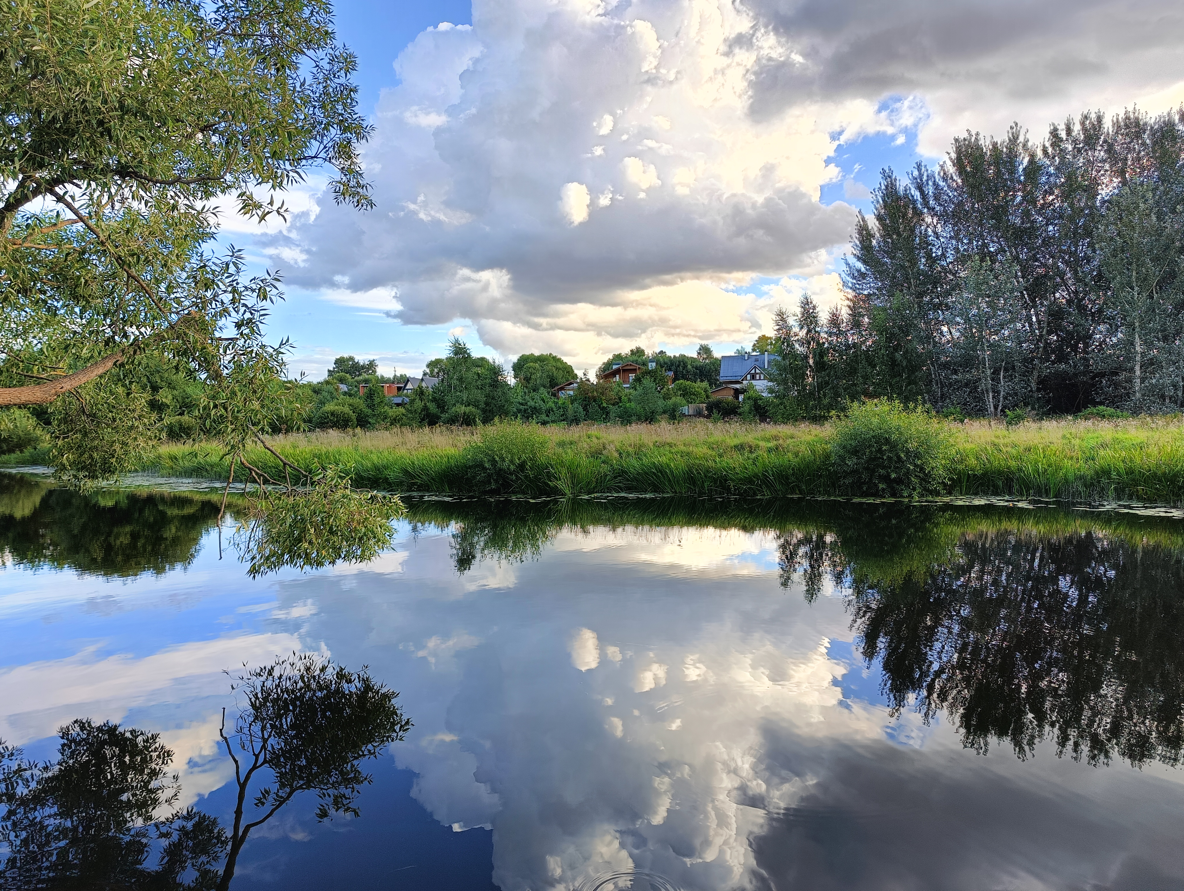 Спокойный пейзаж: река, отражение неба в воде, зелень на берегу